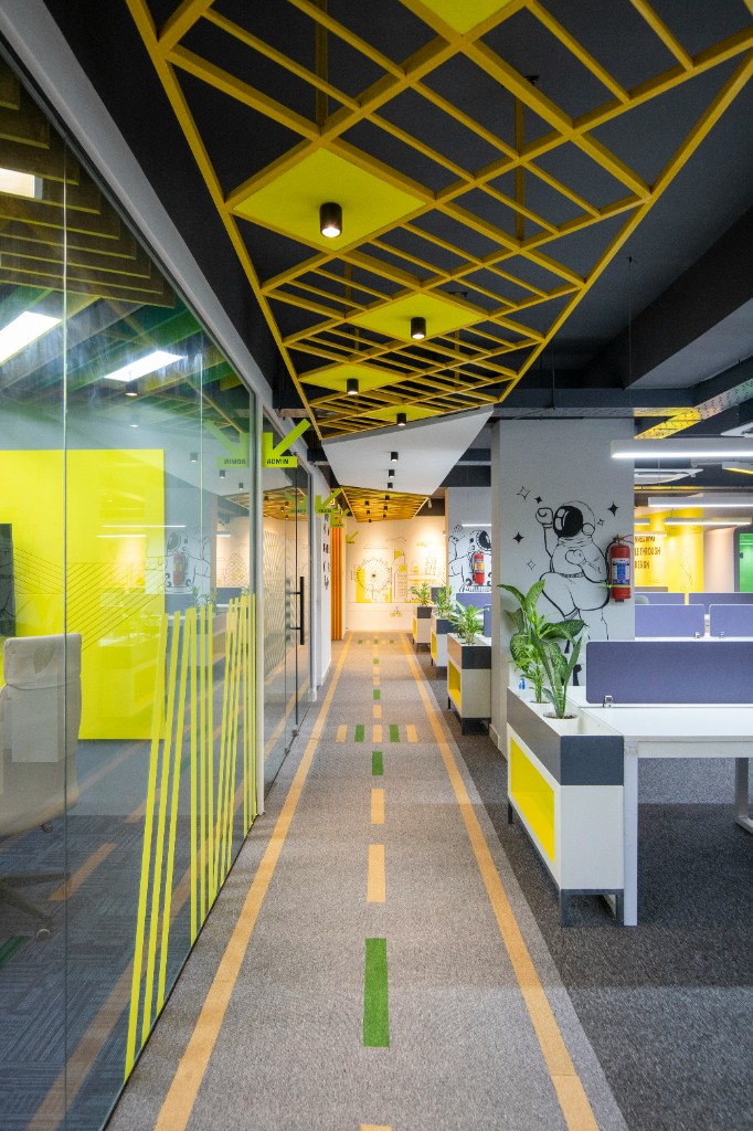 Modern office hall with yellow-accented glass rooms and open workstations