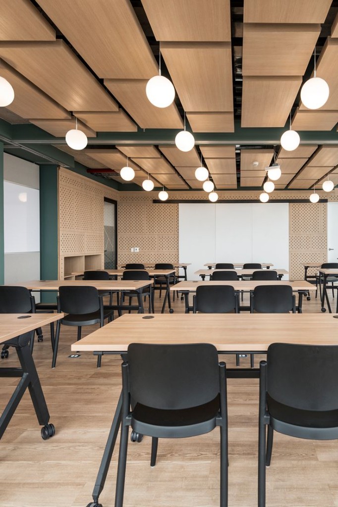 Wood-panel training room with globe pendants and forest green columns