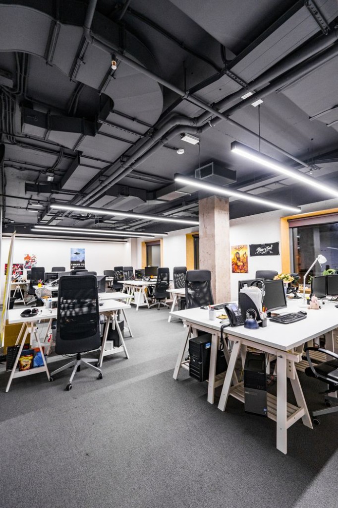 Industrial studio floor with white desks and charcoal ceiling